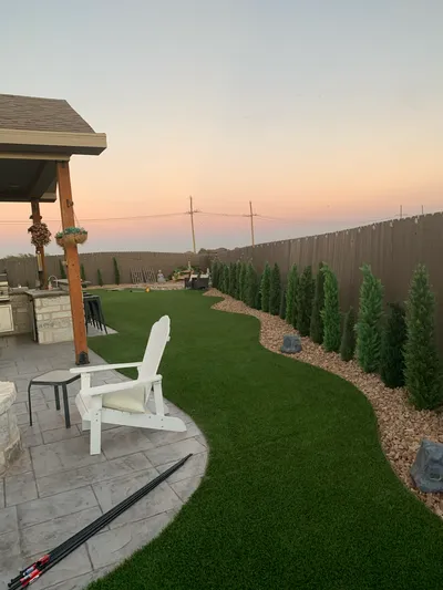 Patio with turf and trees by E and J General Construction