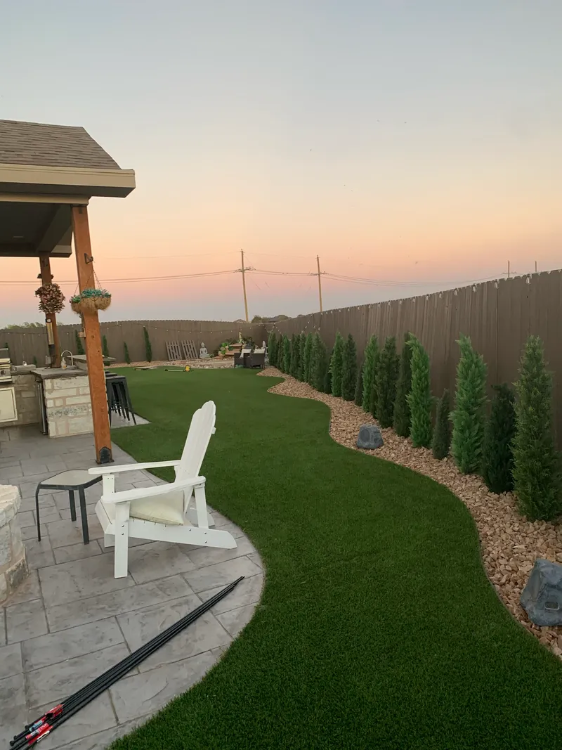 Patio with turf and trees by E and J General Construction